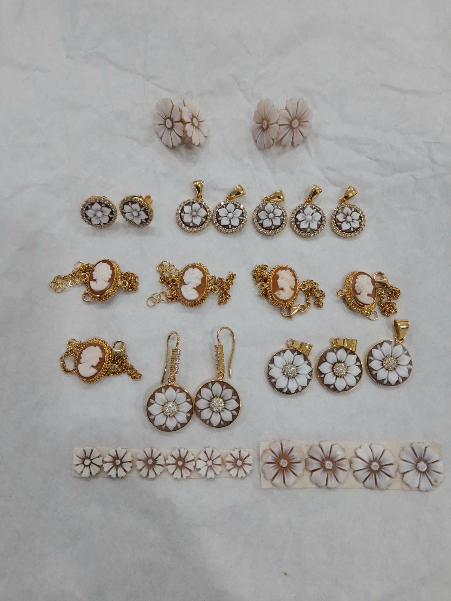 Collection of cameo gold and white floral earrings on a textured surface