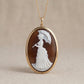 Cameo pendant with a woman holding an umbrella on a beige background