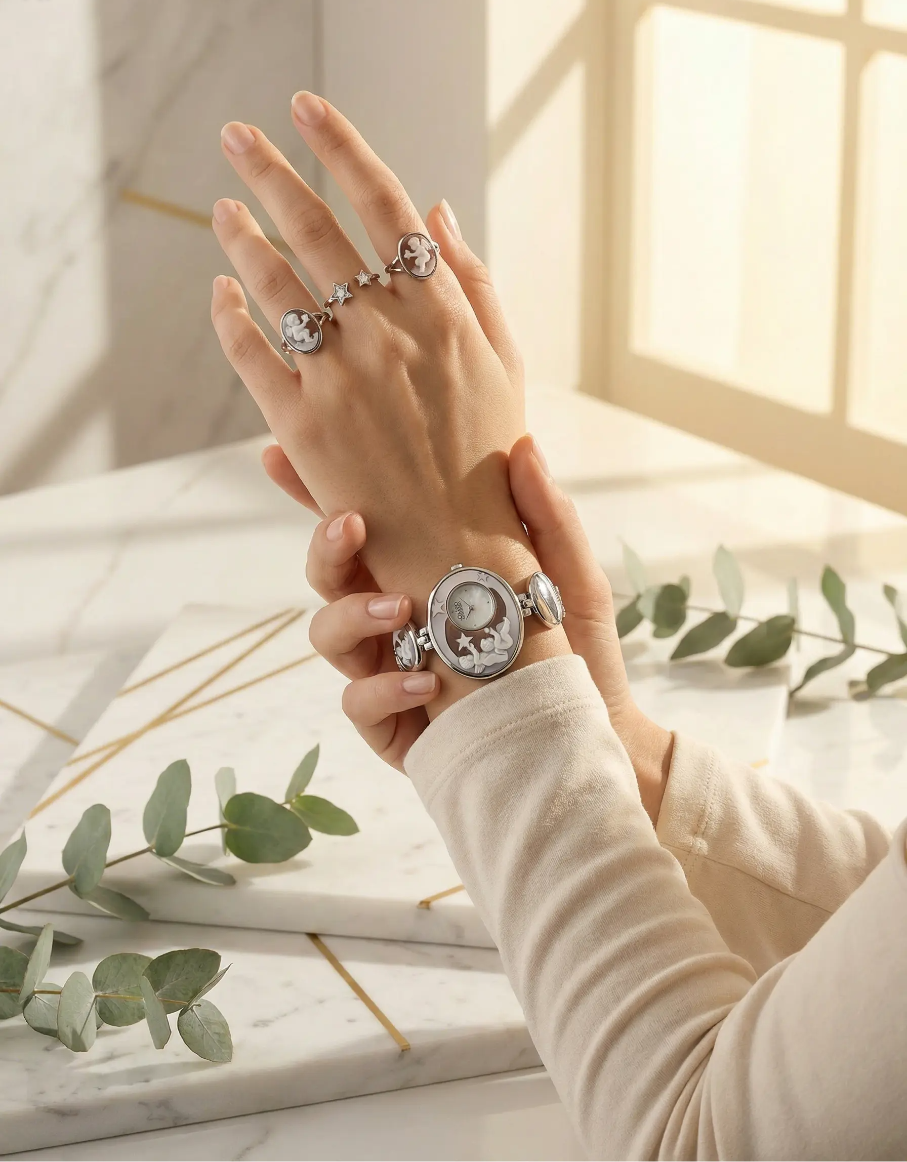 Hand wearing a silver watch with floral design on a marble surface with greenery