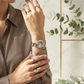 Woman wearing a watch and rings with a neutral background