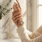 Hand wearing a watch and rings with a marble wall background