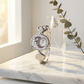 Silver watch with moon and star design on a marble surface with a bottle and plant in the background