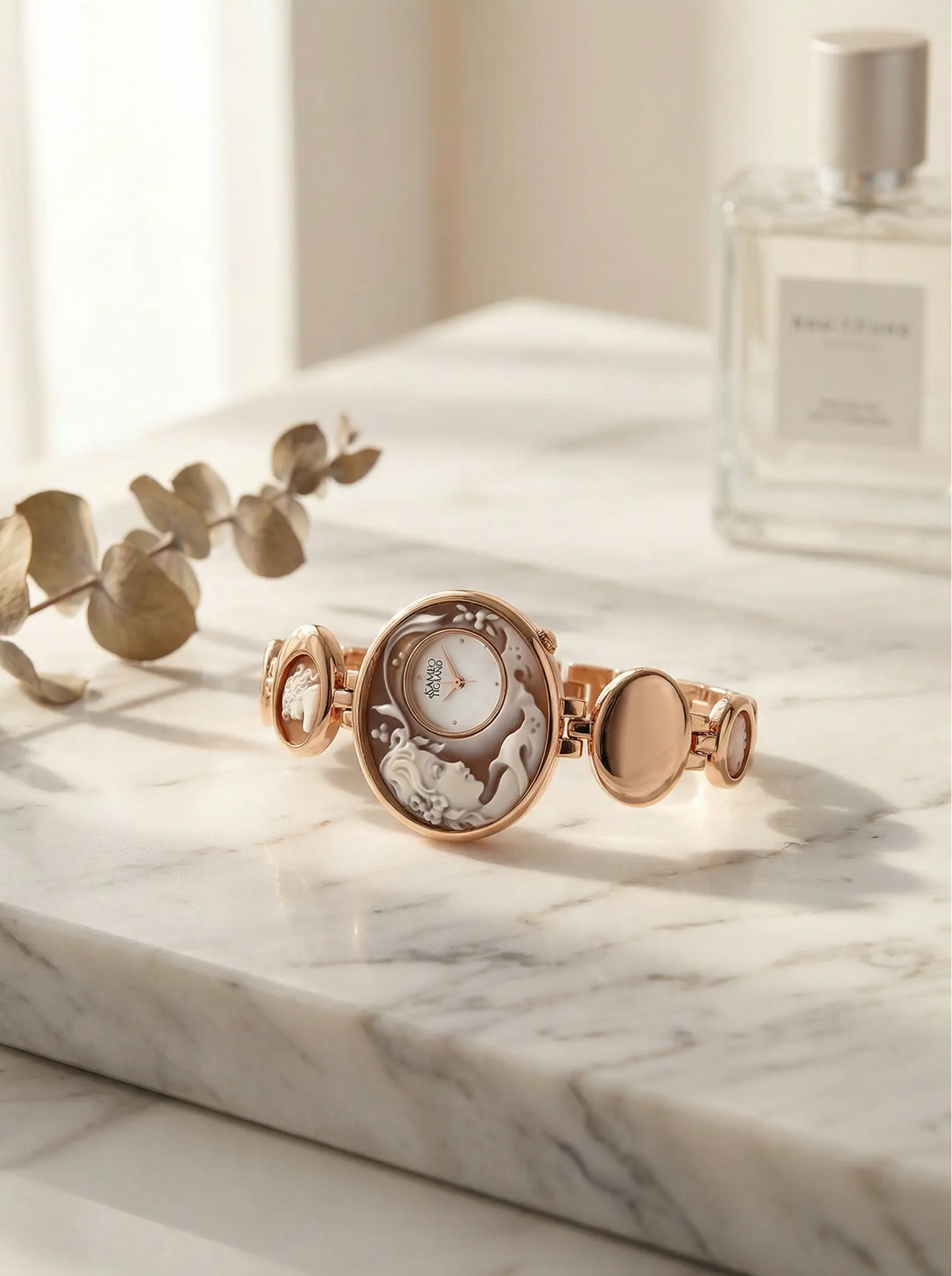 Rose gold bracelet with intricate design on a marble surface next to a bottle of perfume.