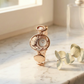 Rose gold watch on a marble surface with a soft focus background