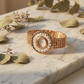 Rose gold bracelet with floral design on a marble surface with green leaves