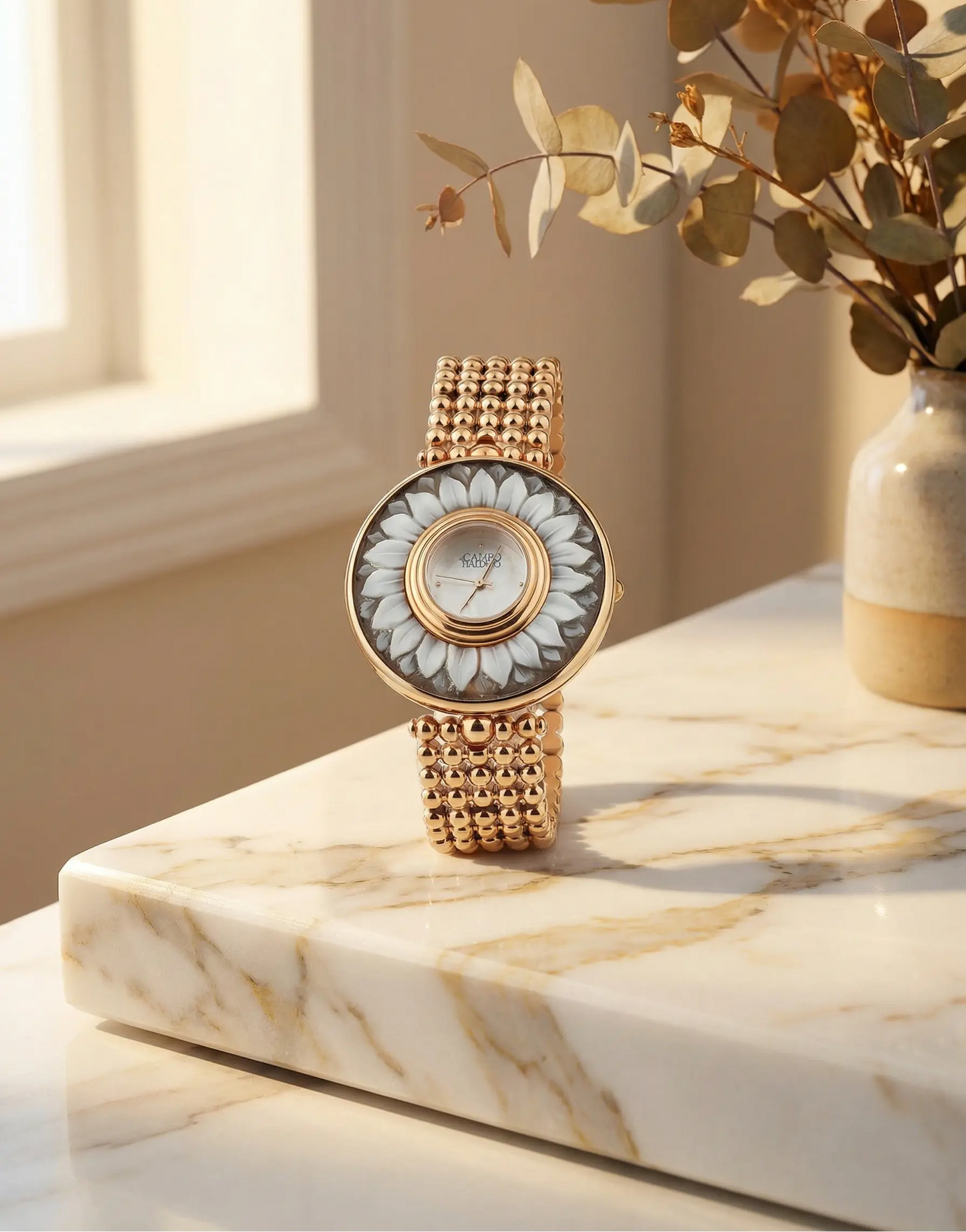 Gold cameo watch with floral design on a marble surface