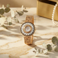 old money Gold watch with floral design on a marble surface with green leaves and a gold box.