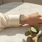 Hand wearing a gold bracelet on a marble surface with a blurred background