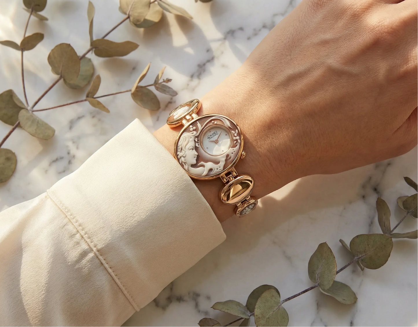 Rose gold watch on a wrist with a marble background and eucalyptus leaves