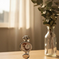 Decorative watch on a wooden surface with a vase of eucalyptus in the background