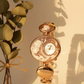 Gold wristwatch with decorative design on a light background